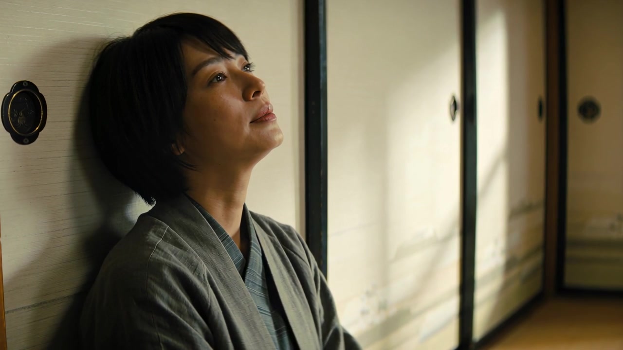 Reacting to soft light, woman in grey kimono beside fusuma raising chin, gazing upward, copy space