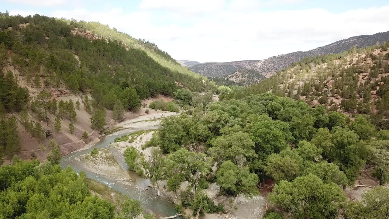 A serene valley nestled in Morocco's Atlas Mountains, where ancient Berber villages dot terraced hillsides, crystal streams flow between rocky peaks, and golden light bathes the rugged terrain