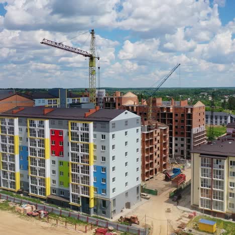 colorful multi-storey building on a construction site. high rise buildings construction site. big industrial tower crane with blue sky on background. aerial drone view. city development