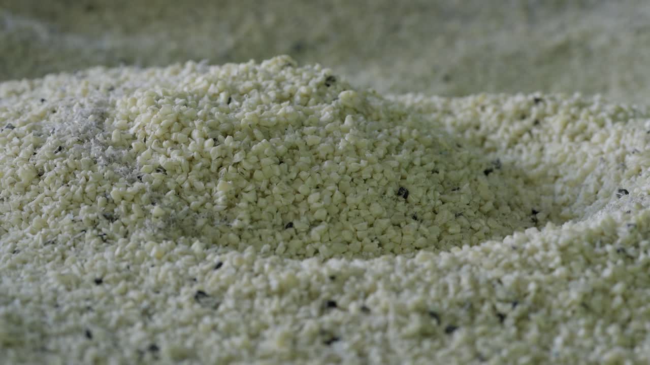 Stor bunke små genanvendte plastgranulat og pellets med mørke pletter på et genbrugsanlæg