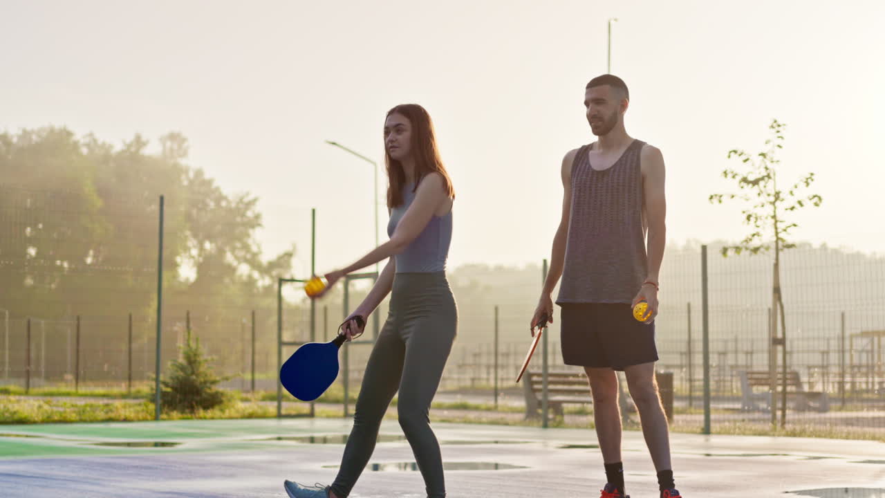 A man teaching a woman how to play pickleball after rain