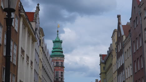 historic tower with green copper roof and weather vane in gdańsk under cloudy sky