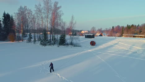 tall caucasian man walks the snow with skis, aerial drone above winter landscape