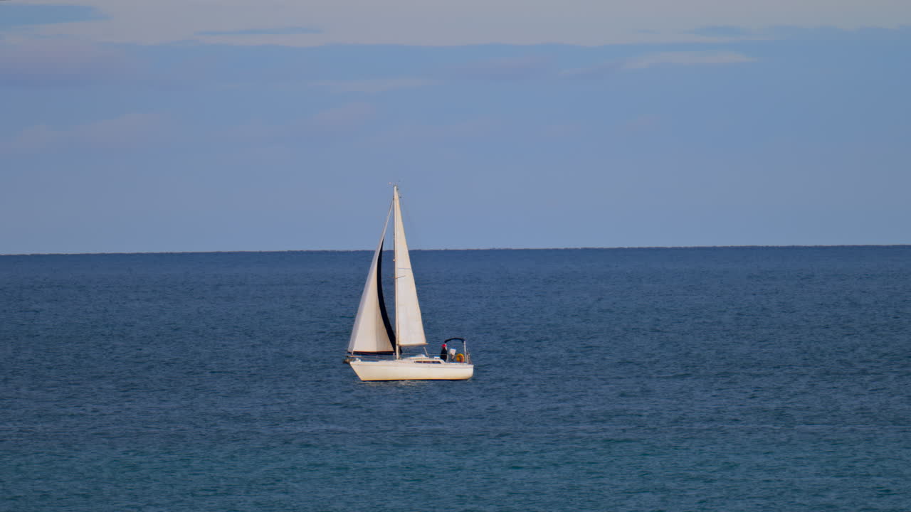 Distant view of a sailing boat moving on the sea
