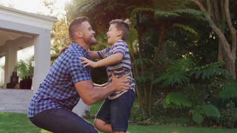 Happy-caucasian-son-running-and-jumping-into-the-arms-of-father-in-garden