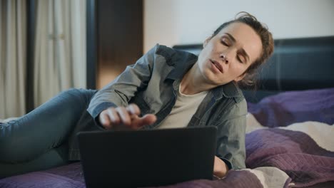 mujer cansada cerrando la computadora portátil en el sofá en casa. mujer molesta terminó el trabajo