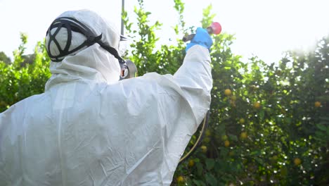agricultor en ropa protectora rociar pesticidas