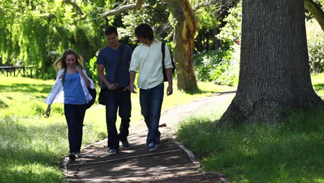 three friends talking to each other as they walk on a park trail