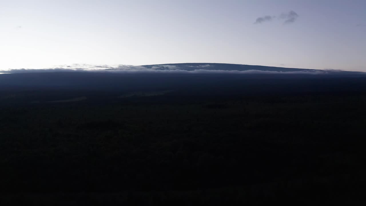 Wide aerial dolly shot of the volcano Mauna Loa silhouetted at sunset on the Big Island of Hawai'i