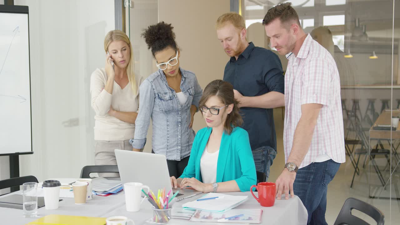mulher com colegas de trabalho assistindo laptop