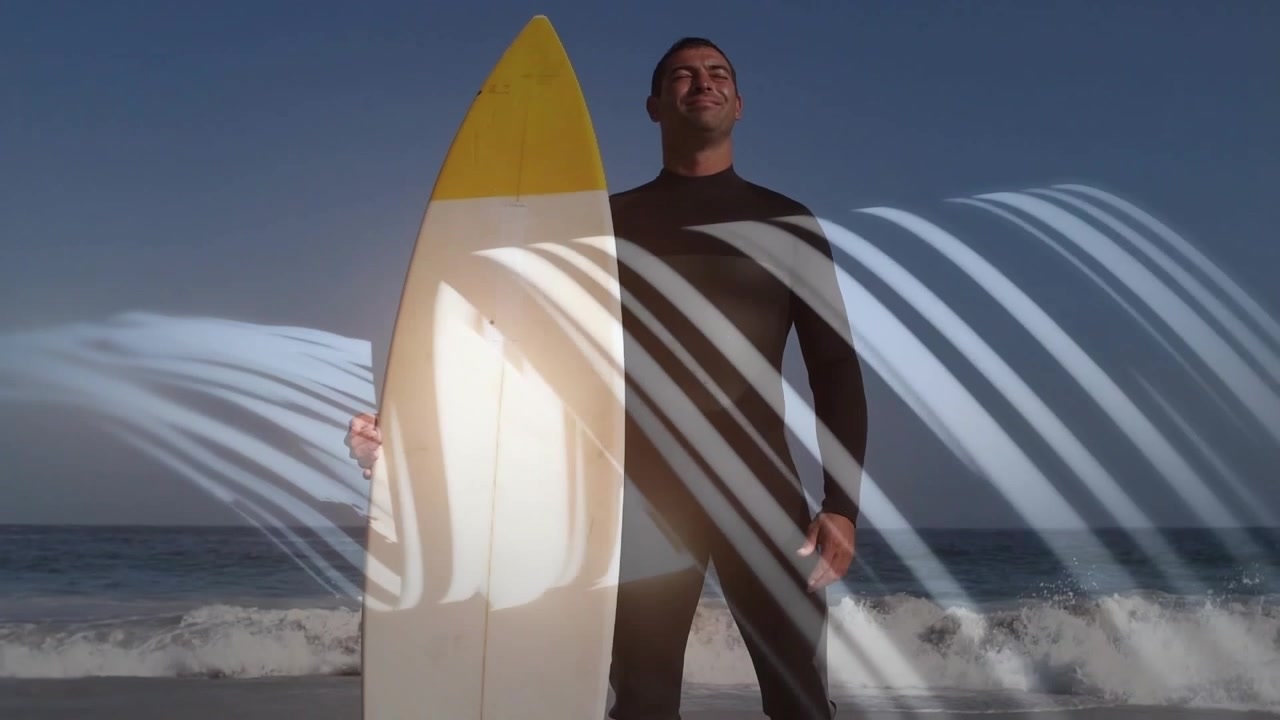 Surfista uomo che arriva sulla sabbia bagnata, spostando il longboard e rivelando il busto della muta mentre si prepara a surfare.
