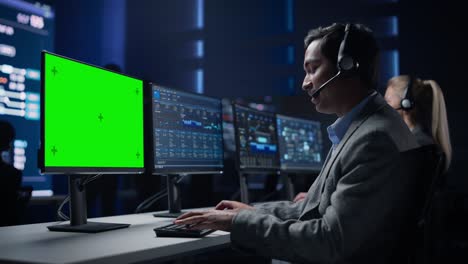 especialista en soporte al cliente habla con el cliente en auriculares trabaja en pantalla clave de croma verde computadora en la sala de control de infraestructura grande. los especialistas usan computadoras que muestran gráficos. habla con los inversores
