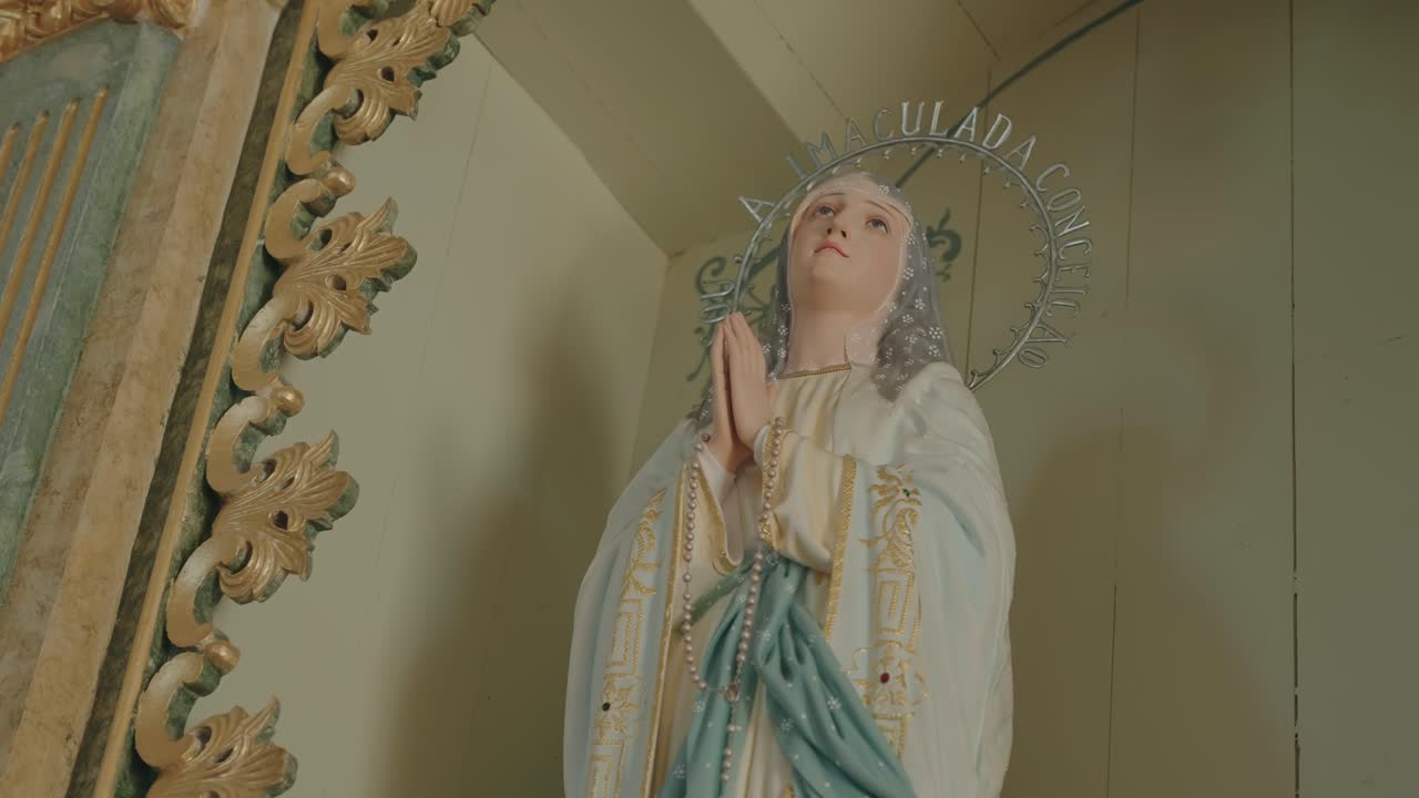 Detailed view of praying Virgin Mary statue in ornate historic church setting