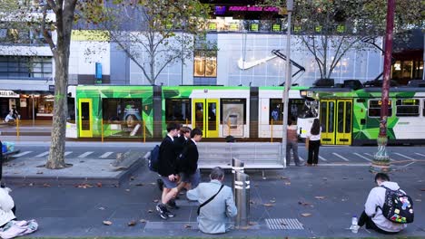 personas caminando y sentadas cerca de un tranvía