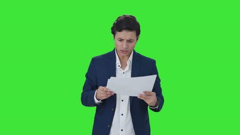 el gerente indio estresado chequeando los informes pantalla verde