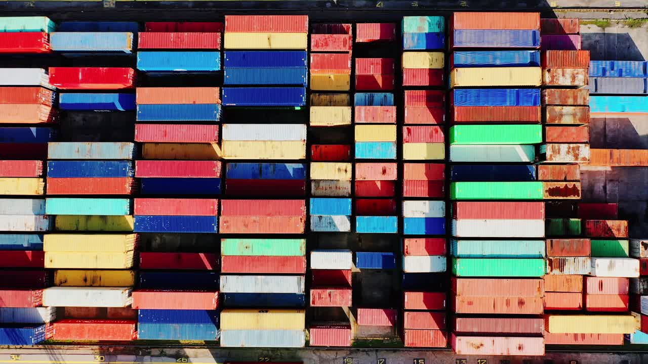 Cinematic top down drone shot of multicolored shipping containers, European port