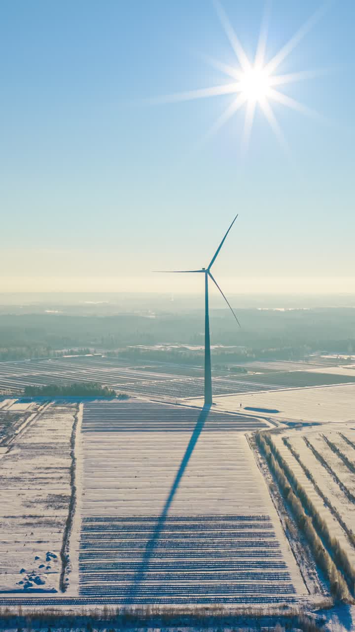 Hyperlapse větrné turbíny v zasněžené krajině pod jasným sluncem.