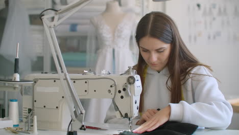 dressmaker sewing clothes. fashion designer sewing new model of clothes. seamstress woman works on sewing machine in tailoring workshop business. she stitches details for future clothing.