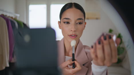 creador de maquillaje aplicando fundación hablando en el apartamento. rutina de rostro de mujer