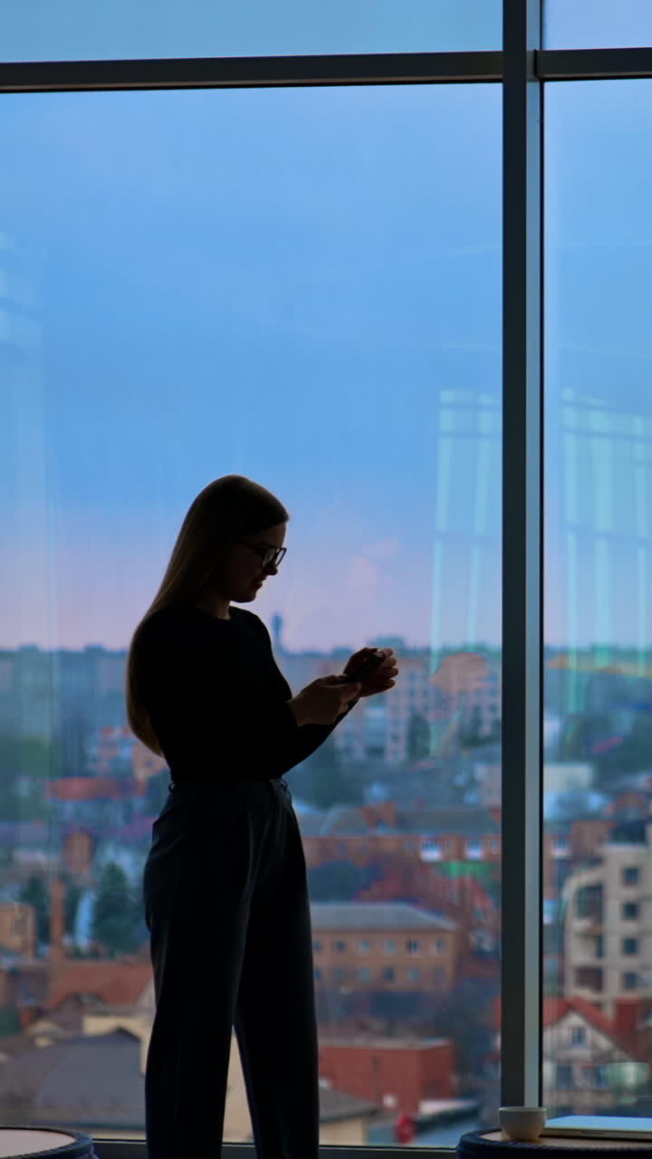 A beautiful smiling woman wearing eyeglasses is using a phone Vertical video