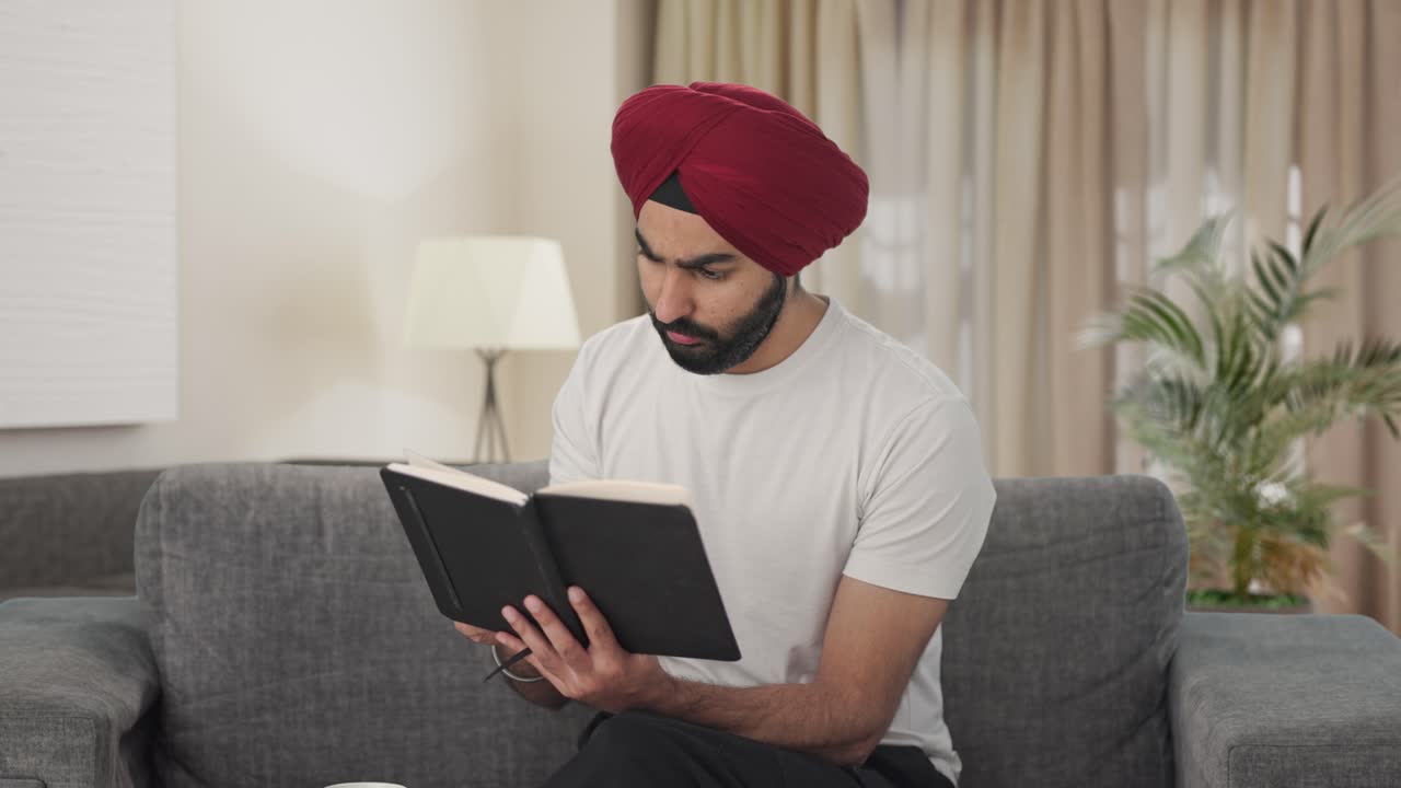 curioso sikh homem indiano lendo um livro e bebendo chá
