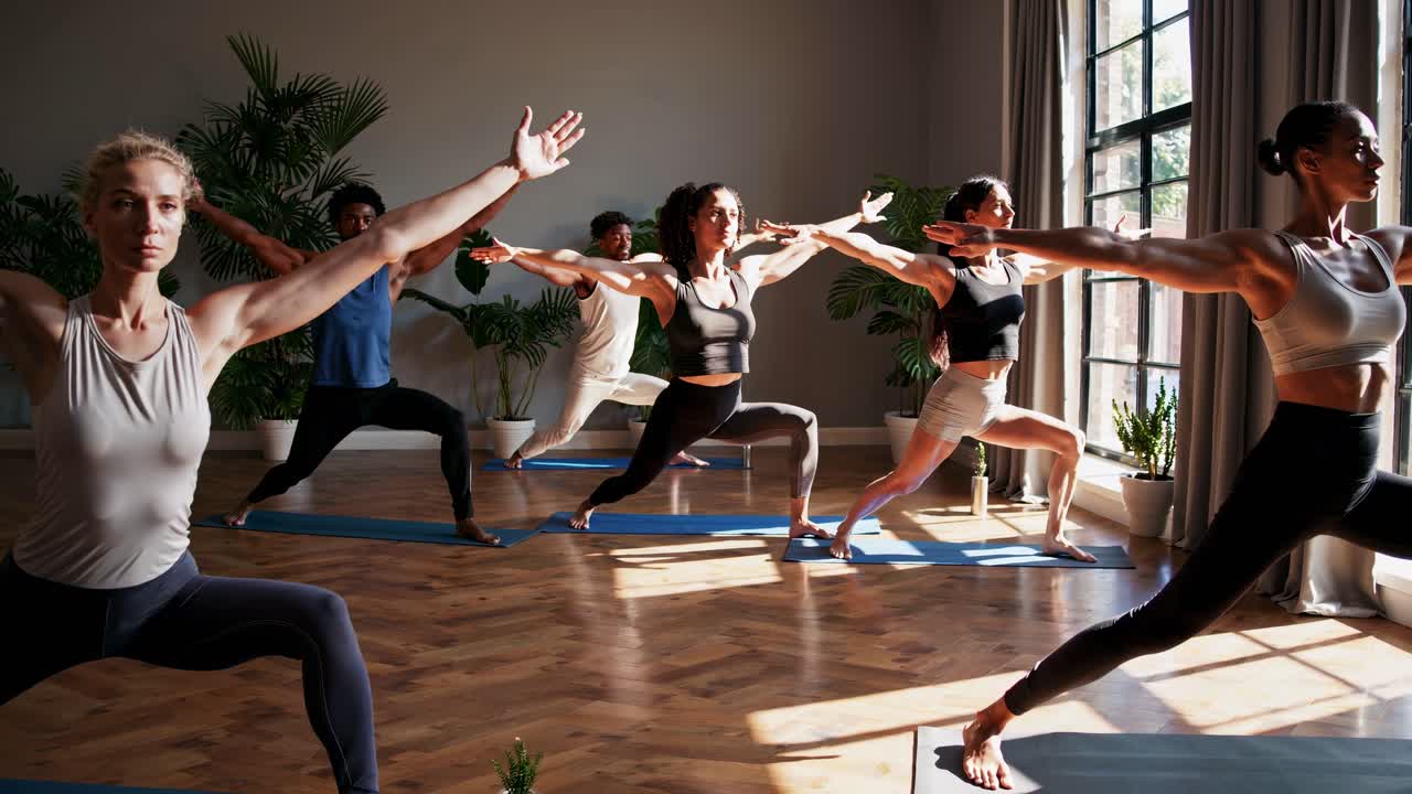 Diverse Group of People Practicing Warrior Pose in Yoga Studio