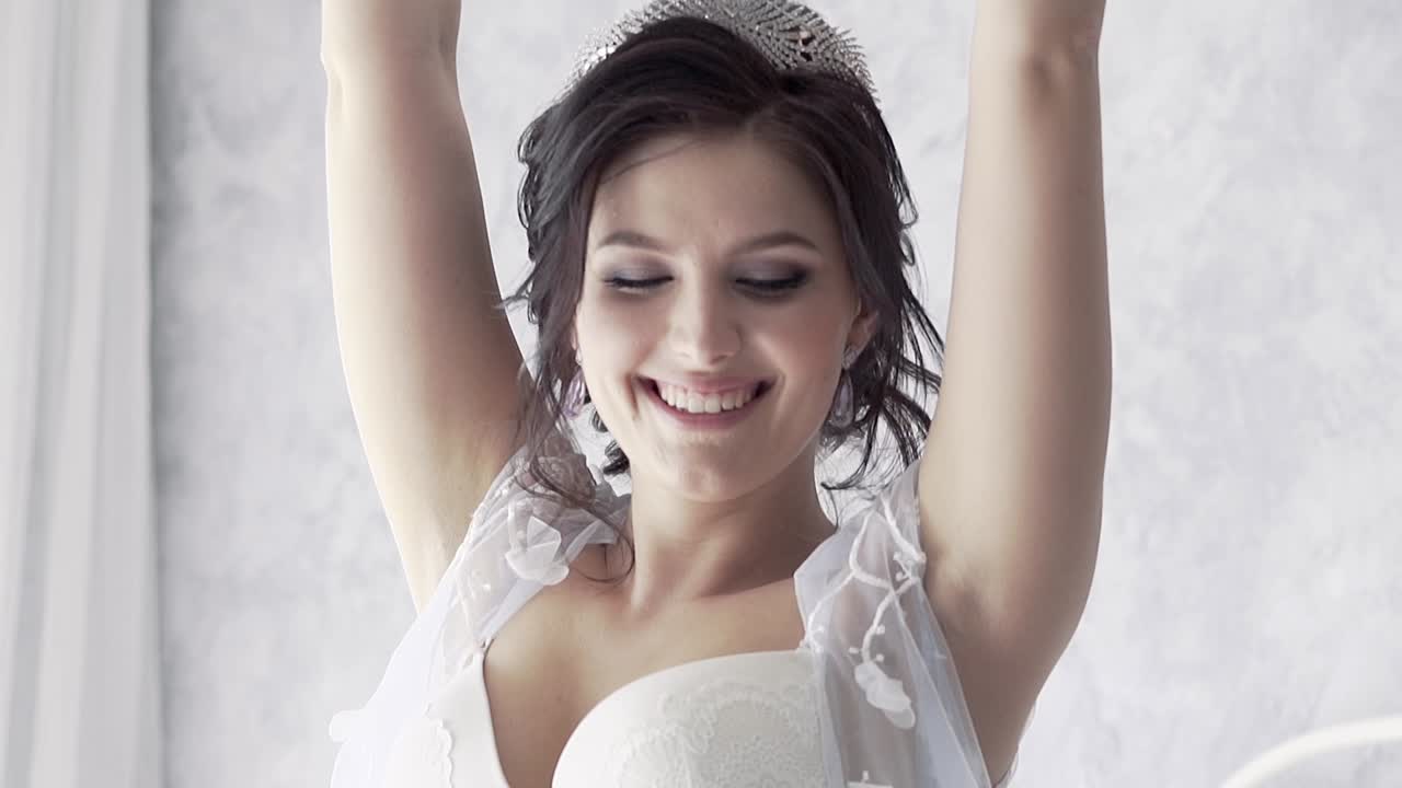 giovane sposa brunetta sorridente in un involucro di pizzo lancia un cuscino