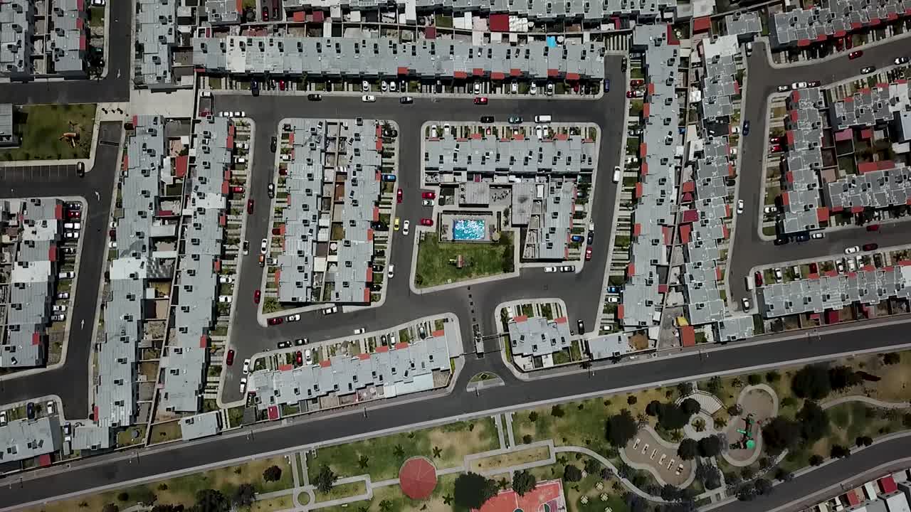 Aerial view from a drone pulling away from a middle-class housing complex featuring a radial swimming pool, located on the outskirts of the city of Querétaro in central Mexico