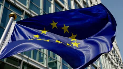 european union flag flying in front of modern building