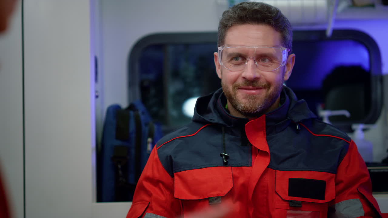 응급차에 앉아 있는 미소 짓는 구급대원. 의사 는 동료 와 이야기 하고 있다