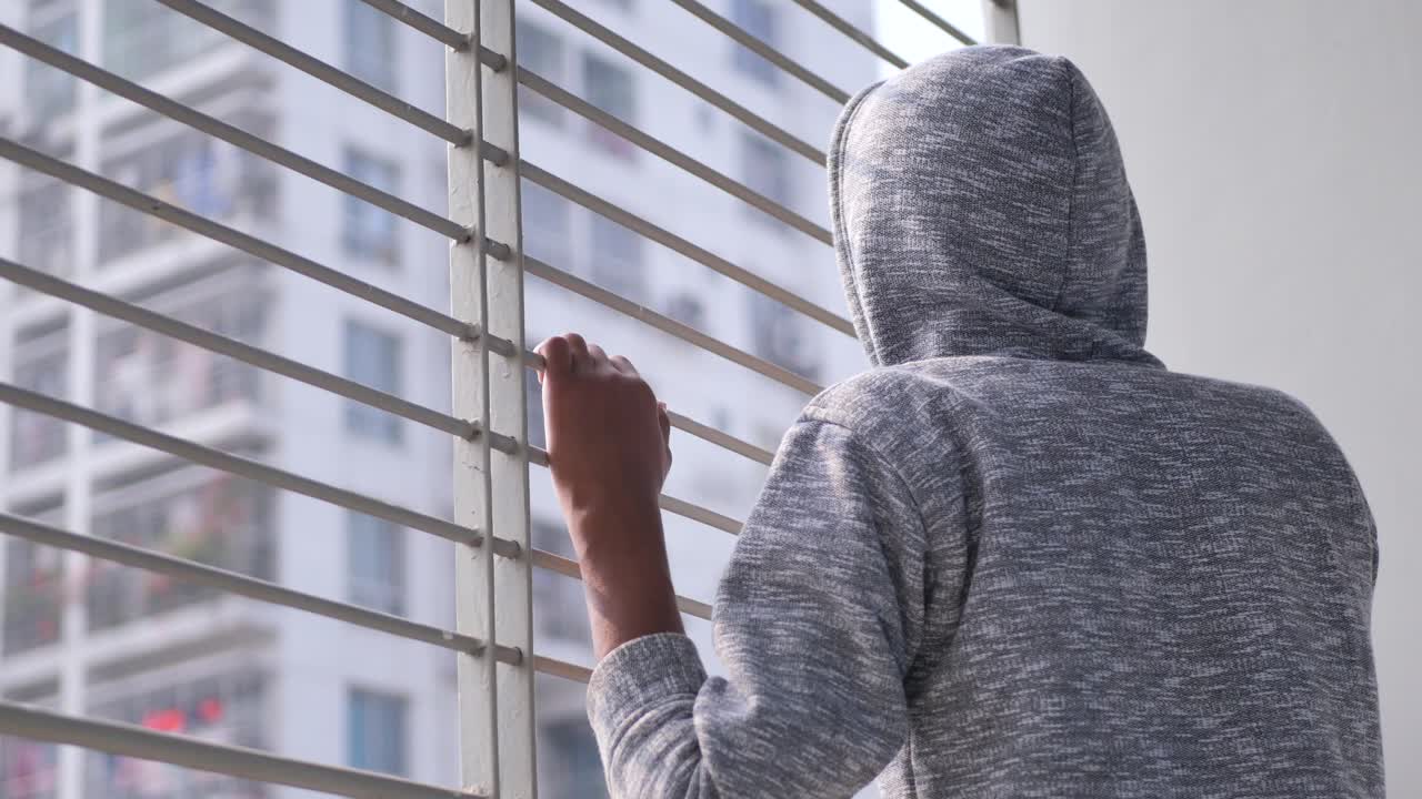 un adolescente triste mirando por la ventana
