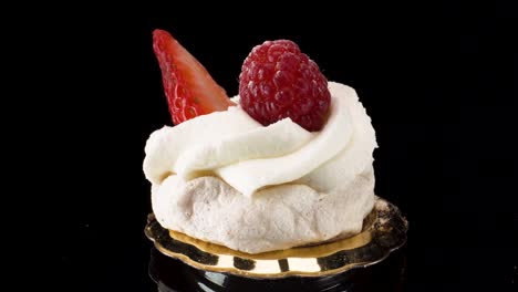 macro-view-turning-mini-pavlova-on-black-reflective-glass-background,-mini-luxury-patisserie,-sweet-dessert-closeup