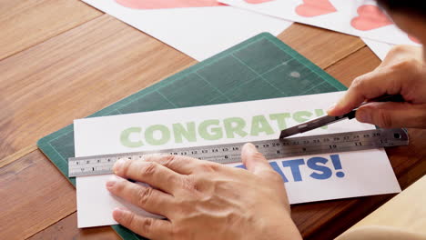 Close-up-of-hands-cutting-paper-using-utility-knife-cutter-with-ruler-on-cutting-mat