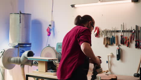 Man-uses-orbital-sander-gear-after-consulting-schematics,-assisted-by-apprentice