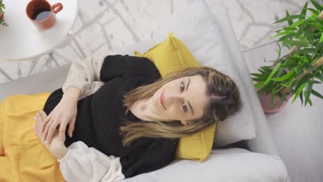 Woman-lying-on-sofa-at-home-relaxing-and-daydreaming.