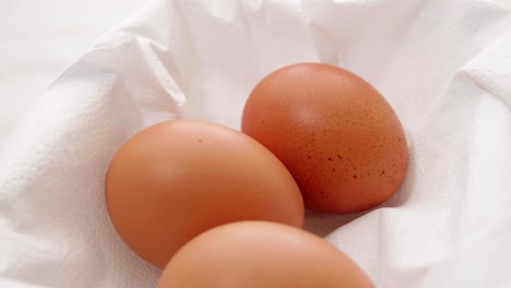 three organic fresh eggs in a rotating container on white wrapping paper for making food