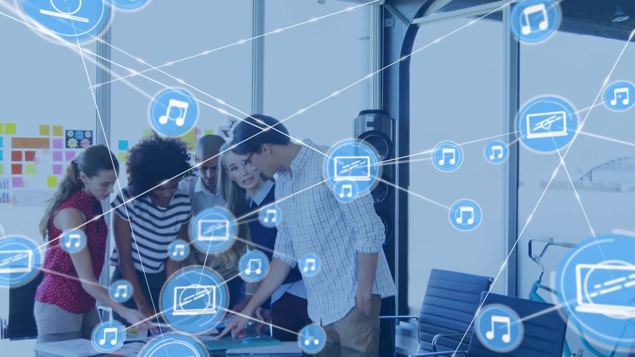 Equipo de negocios tocando una tableta y señalando, iniciando iconos azules que se conectan a una red que cubre la mesa.