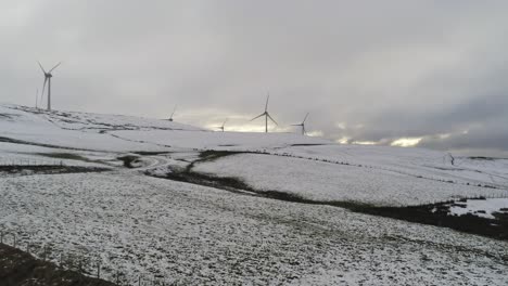 winter mountain countryside wind turbines on rural highlands aerial right panning view cold snowy valley hillside