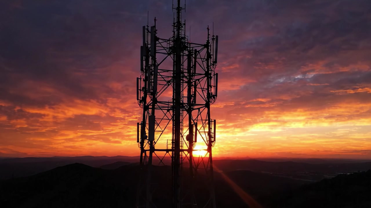 Una torre contro un tramonto mozzafiato: ammira la maestosa esposizione di colori e la silhouette di una struttura di comunicazione in mezzo a un paesaggio celeste drammatico.