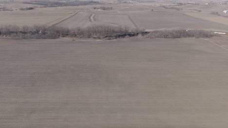 Vast-Swathes-of-agricultural-land,-interrupted-only-by-a-wide,-meandering-river,-from-the-air