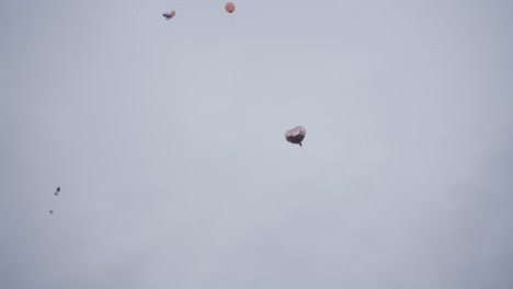 Globo-De-Corazón-Plateado-Vuela-Lentamente-Por-Una-Casa-Hacia-El-Cielo-En-El-Fondo-Se-Pueden-Ver-Más-Globos