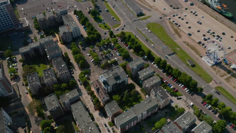 Aerial-footage-of-housing-estate,-tilt-up-reveal-of-wide-river-and-busy-multi-lane-road-leading-on-waterfront.-High-angle-view-of-city