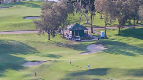 drone captures golfers on a lush green fairway at gold coast, australia. bright daylight highlights the serene golfing environment