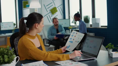 Woman-comparing-statistics-with-sales-charts-on-laptop-and-taking-a-break-to-drink-coffee-or-tea