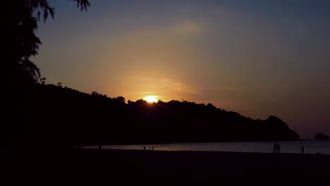 time lapse of sunset behind the hill, across the beach and sea.
