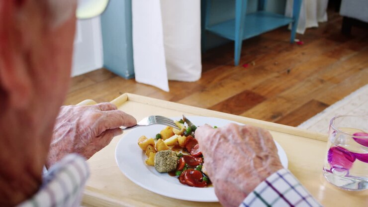 Over shoulder view of senior man eating dinner at home