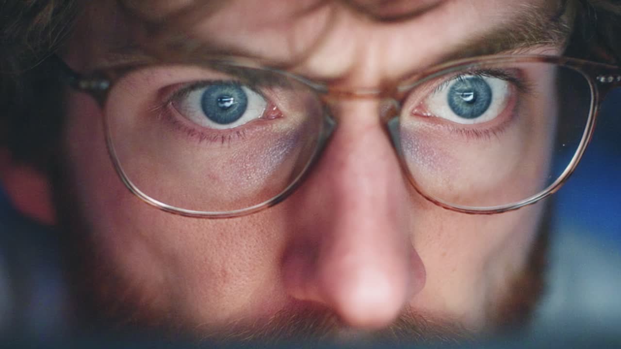 Intense Focus: A Close-Up of Eyes Behind Glasses Revealing Concentration and Engagement with an Unseen Digital World