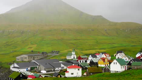 Panorámica-A-Través-De-Un-Tranquilo-Valle-Lleno-De-Niebla-Sobre-Casas-Con-Techo-De-Césped-En-La-Aldea-De-Gjogv,-Eysturoy,-Islas-Feroe.