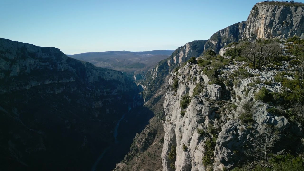 Uma imagem de drone matinal com vista para o vasto Desfiladeiro de Verdon, Gorges du Verdon, na França. Paredes rochosas mergulham abruptamente nas profundezas. Um jogo de luz e sombra no desfiladeiro