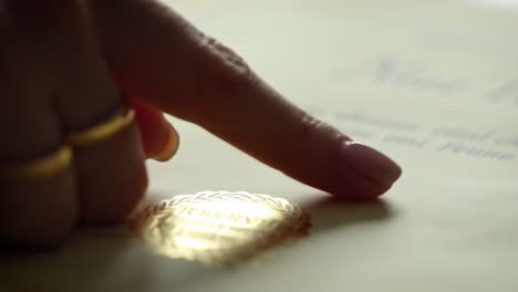 a close-up exploration of an elegant document, highlighting a finger touching a decorative seal symbolizing achievement or certification